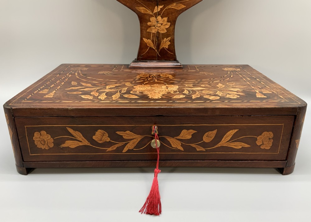 A 19th-century Dutch marquetry toilet mirror featuring a circular swivelling glass frame supported by carved wooden arms above a single base drawer decorated with detailed floral timber inlays. View IV