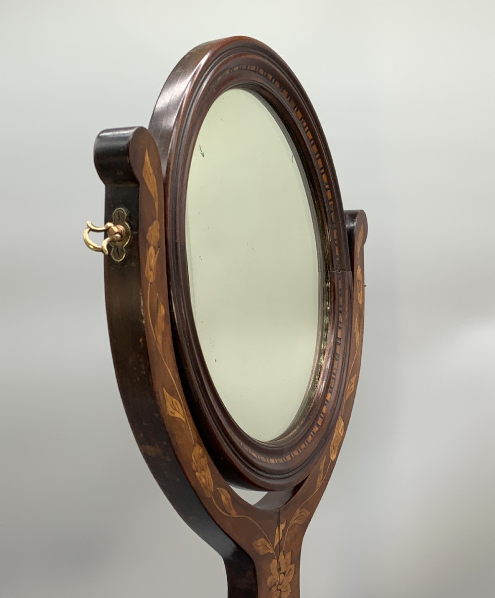A 19th-century Dutch marquetry toilet mirror featuring a circular swivelling glass frame supported by carved wooden arms above a single base drawer decorated with detailed floral timber inlays. View XII