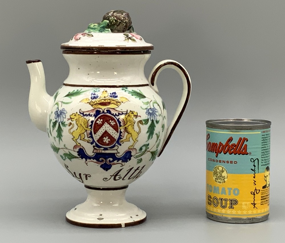 An 18th-century Italian tin-glazed earthenware pharmacy wet drug jug with a spouted body, top handle, lid with sculpted finial, painted armorial crest, floral scrolls, and Latin text reading Syr Alth. View III