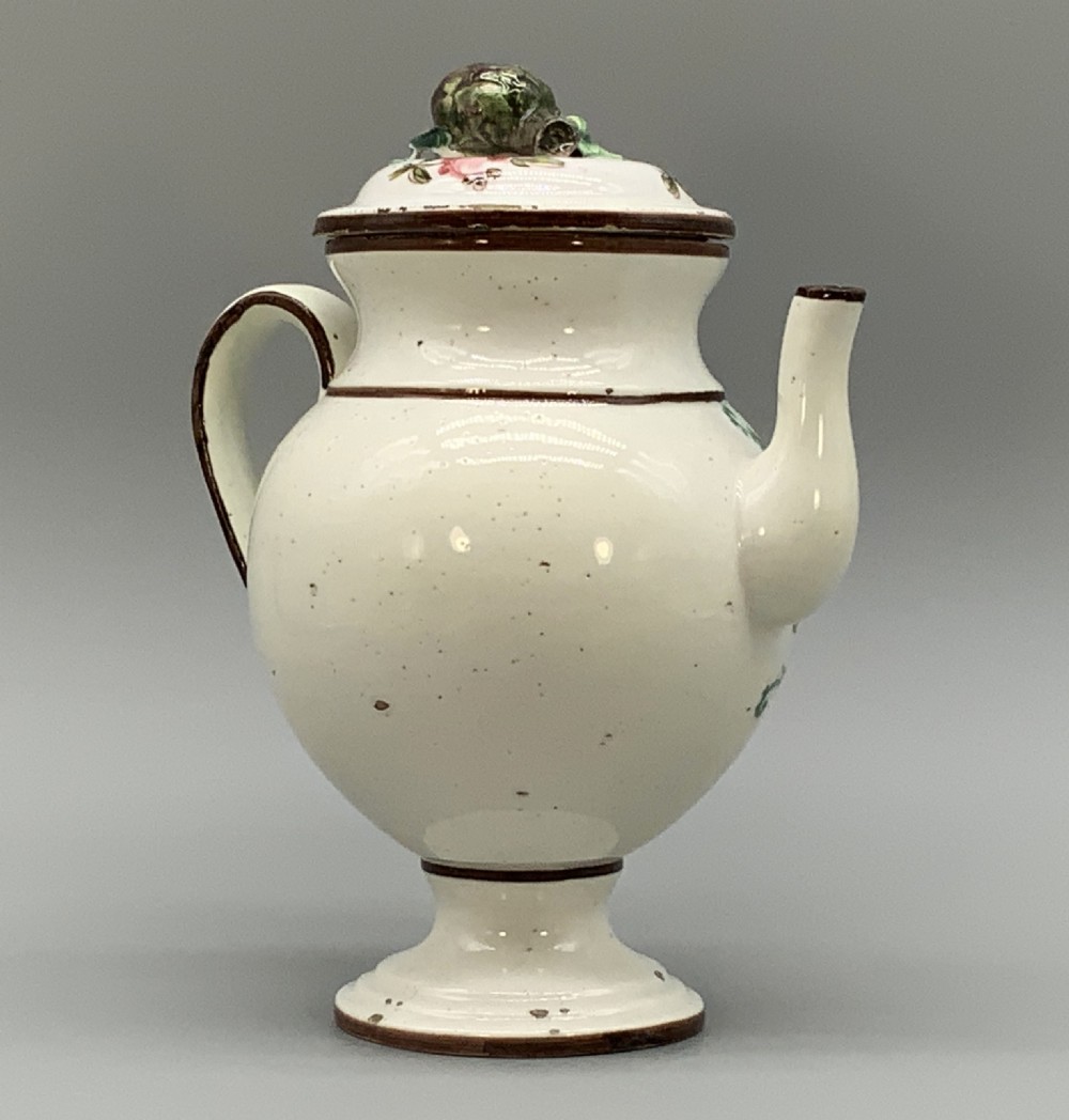 An 18th-century Italian tin-glazed earthenware pharmacy wet drug jug with a spouted body, top handle, lid with sculpted finial, painted armorial crest, floral scrolls, and Latin text reading Syr Alth. View VII
