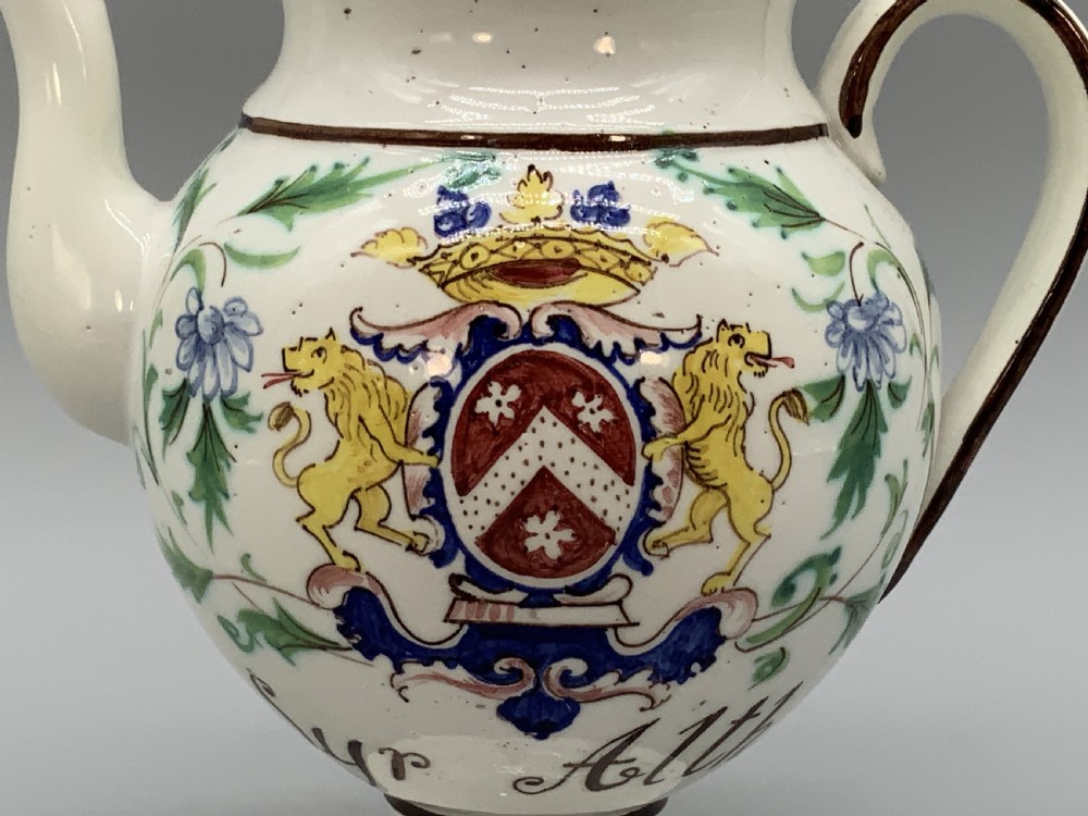 An 18th-century Italian tin-glazed earthenware pharmacy wet drug jug with a spouted body, top handle, lid with sculpted finial, painted armorial crest, floral scrolls, and Latin text reading Syr Alth. View XII