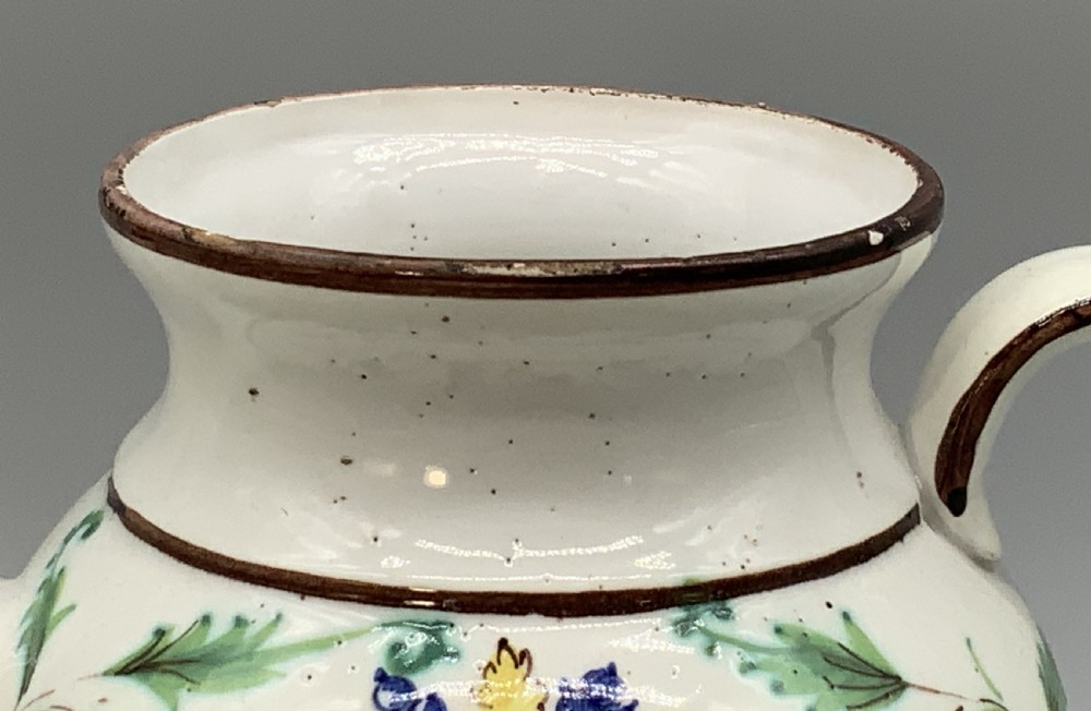 An 18th-century Italian tin-glazed earthenware pharmacy wet drug jug with a spouted body, top handle, lid with sculpted finial, painted armorial crest, floral scrolls, and Latin text reading Syr Alth. View XIV