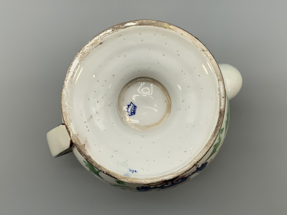 An 18th-century Italian tin-glazed earthenware pharmacy wet drug jug with a spouted body, top handle, lid with sculpted finial, painted armorial crest, floral scrolls, and Latin text reading Syr Alth. View XIX