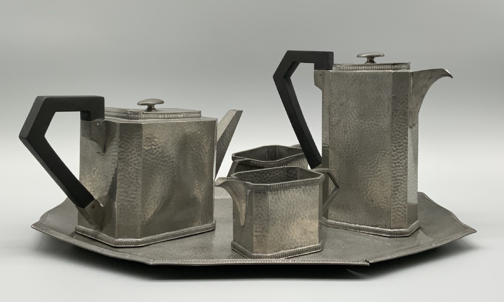 A five-piece Art Deco pewter tea and coffee set featuring a planished finish, geometric handles, and an octagonal tray. View II