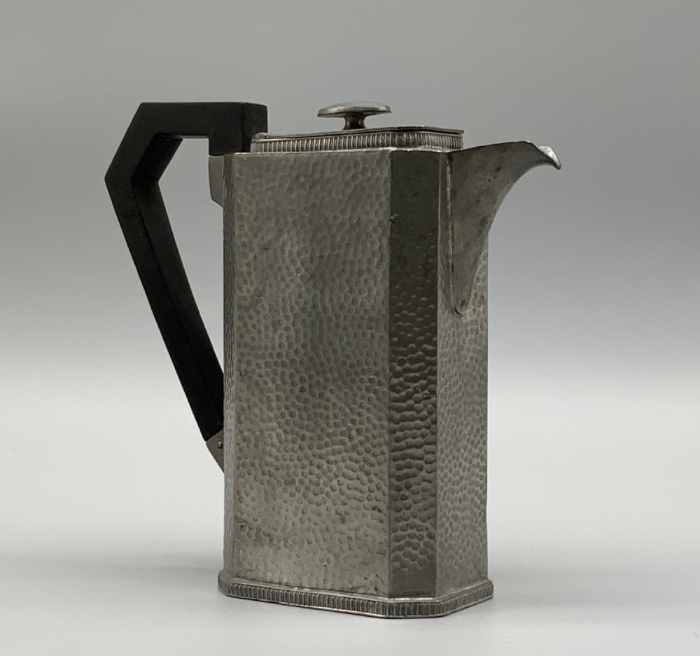 A five-piece Art Deco pewter tea and coffee set featuring a planished finish, geometric handles, and an octagonal tray. View VI
