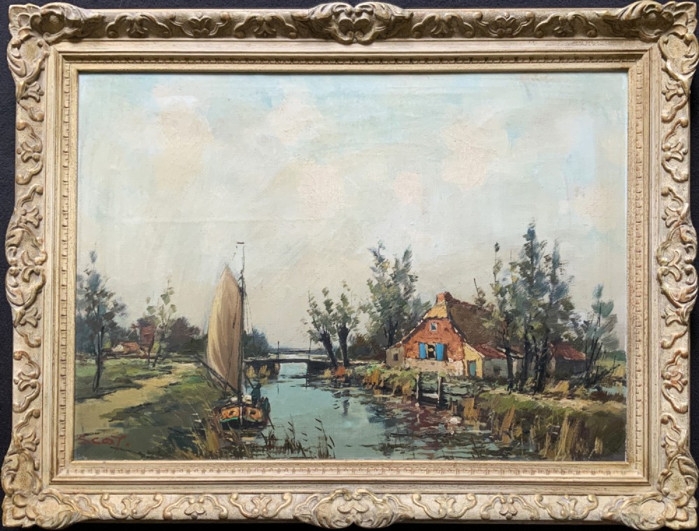 An impressionist oil painting depicting a river scene with a sailboat, a cottage with blue shutters, and trees set in an ornate carved light cream frame.