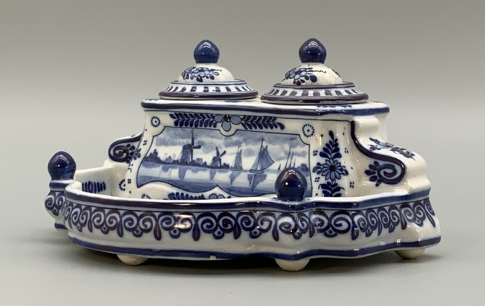A late nineteenth-century Dutch Delft blue and white ceramic inkstand featuring twin removable lids, an integrated pen tray, and hand-painted windmill landscape scenes. View V