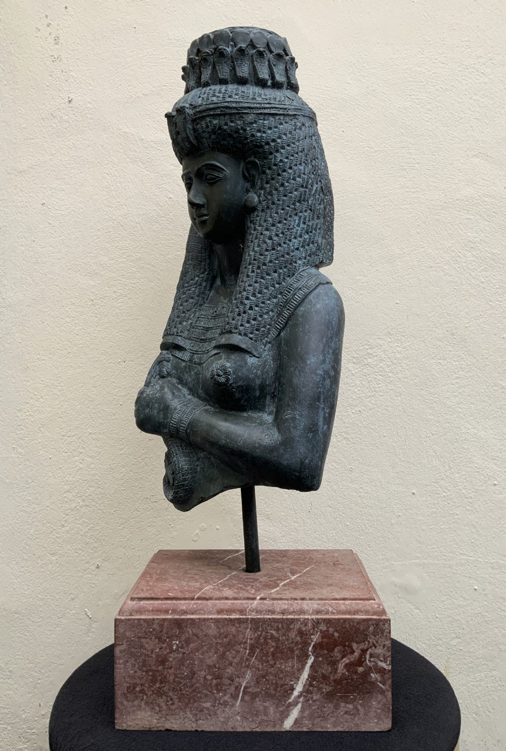 A dark green patinated bronze bust of Cleopatra holding an asp, mounted on a rectangular pink marble base. View V
