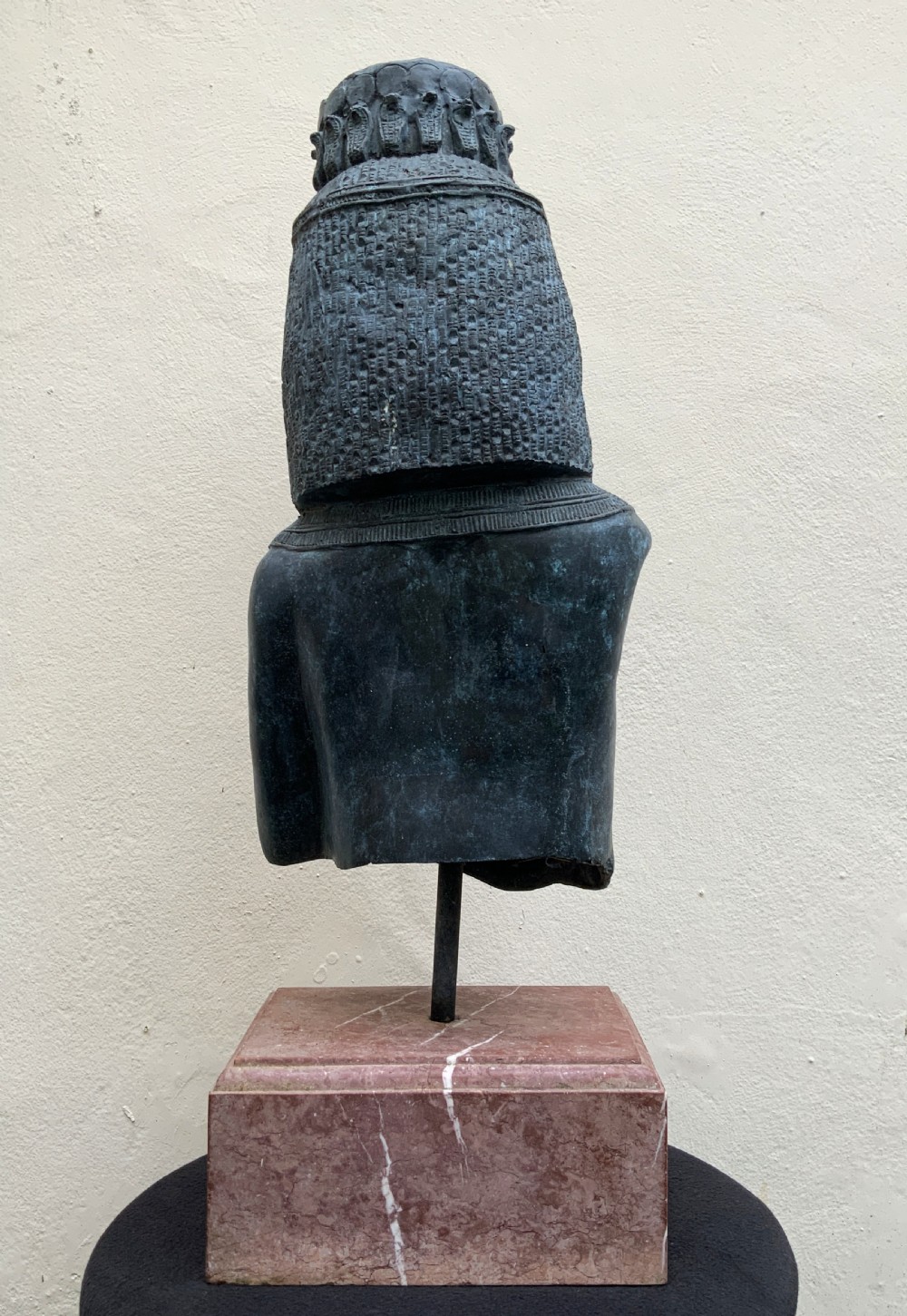 A dark green patinated bronze bust of Cleopatra holding an asp, mounted on a rectangular pink marble base. View VI