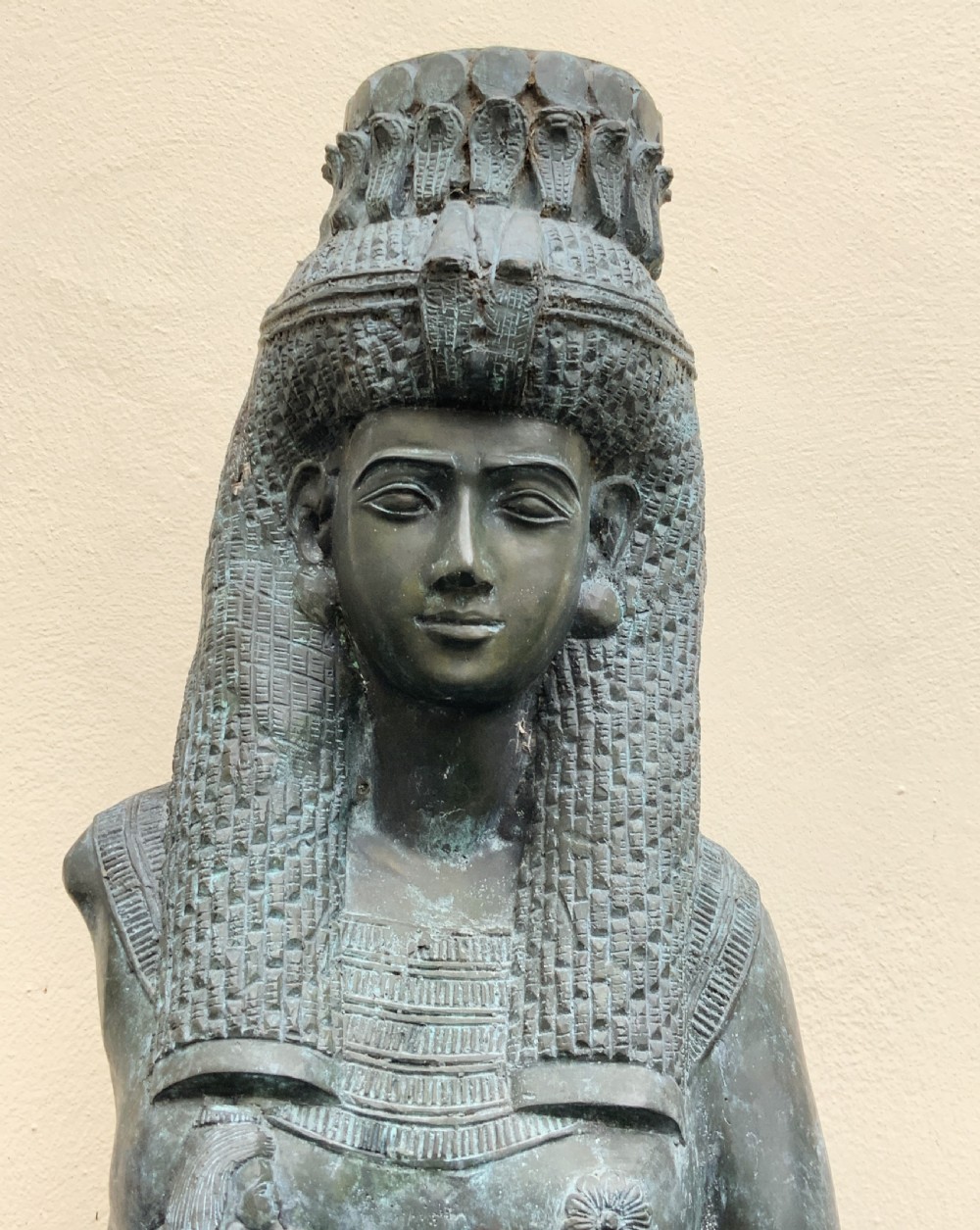 A dark green patinated bronze bust of Cleopatra holding an asp, mounted on a rectangular pink marble base. View VIII