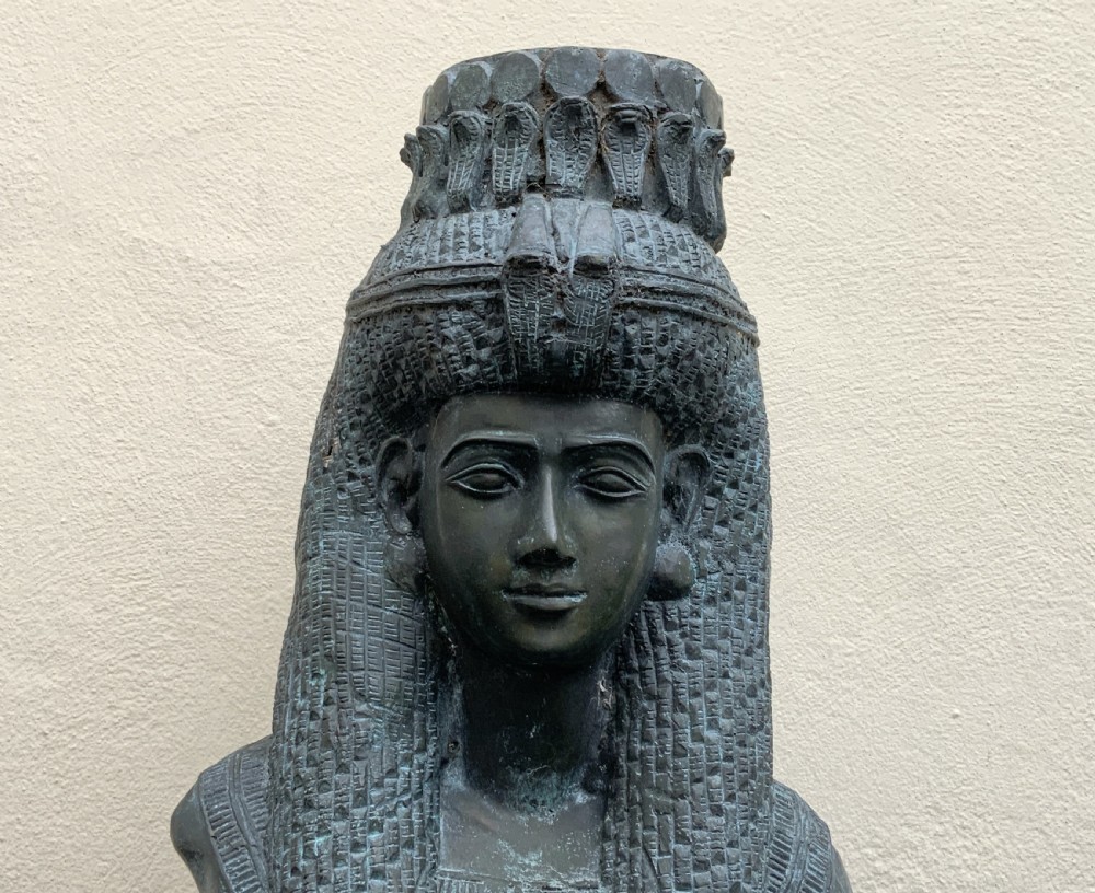 A dark green patinated bronze bust of Cleopatra holding an asp, mounted on a rectangular pink marble base. View XI