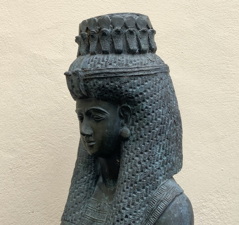 A dark green patinated bronze bust of Cleopatra holding an asp, mounted on a rectangular pink marble base. View XII