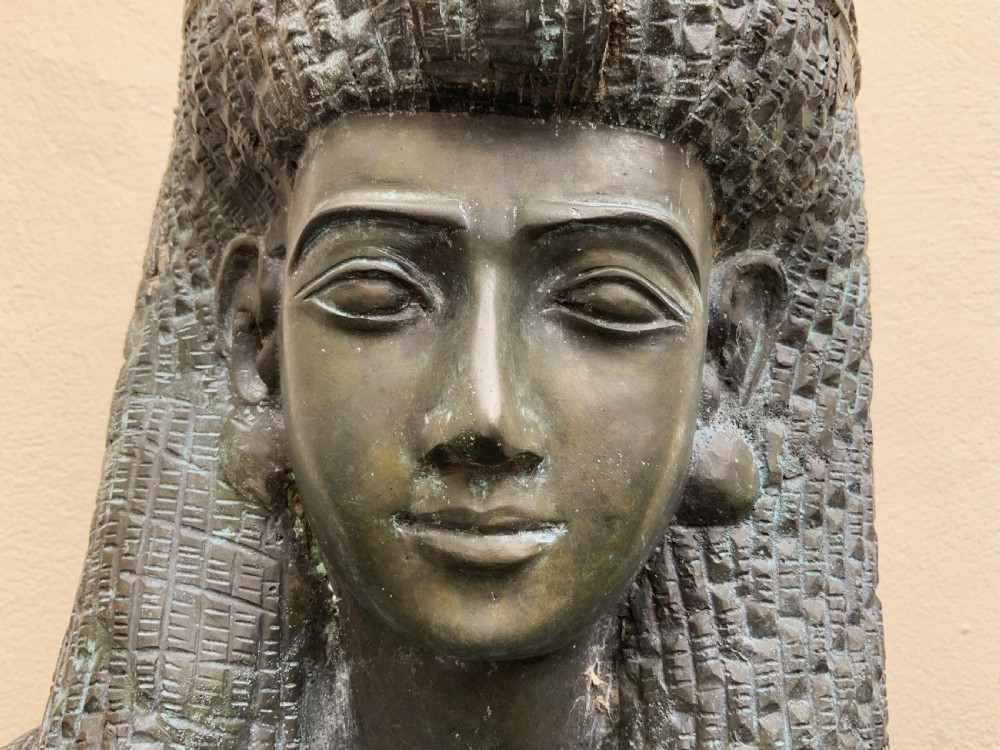 A dark green patinated bronze bust of Cleopatra holding an asp, mounted on a rectangular pink marble base. View XX
