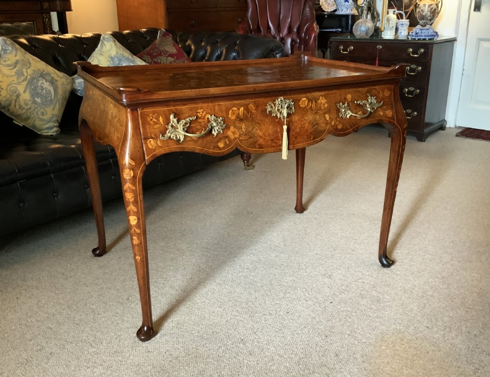 An 18th-century Dutch walnut tea table featuring floral fruitwood marquetry inlays, a tray top, brass handles, and cabriole legs.