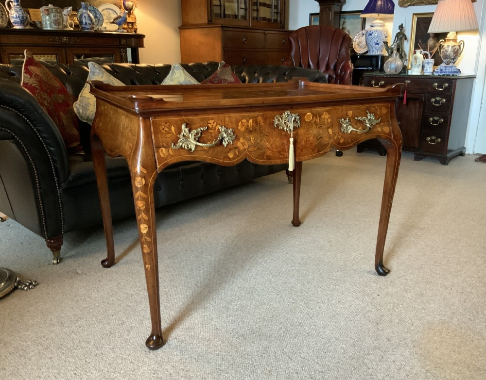 An 18th-century Dutch walnut tea table featuring floral fruitwood marquetry inlays, a tray top, brass handles, and cabriole legs. View V