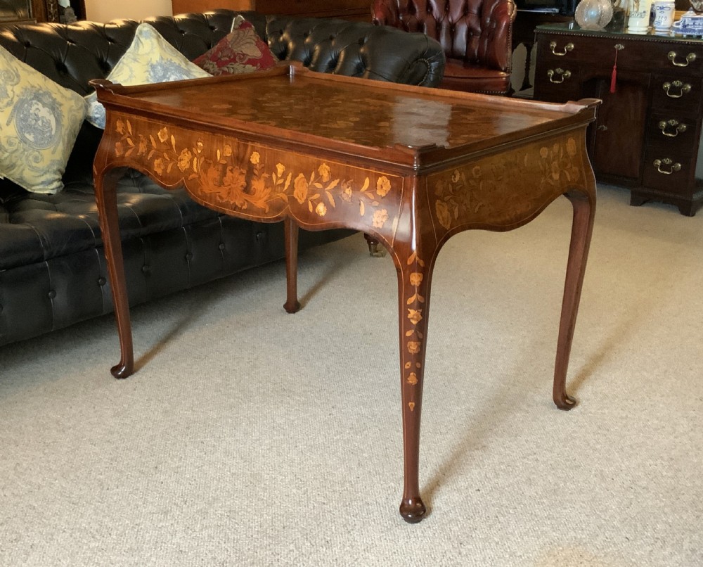 An 18th-century Dutch walnut tea table featuring floral fruitwood marquetry inlays, a tray top, brass handles, and cabriole legs. View VI