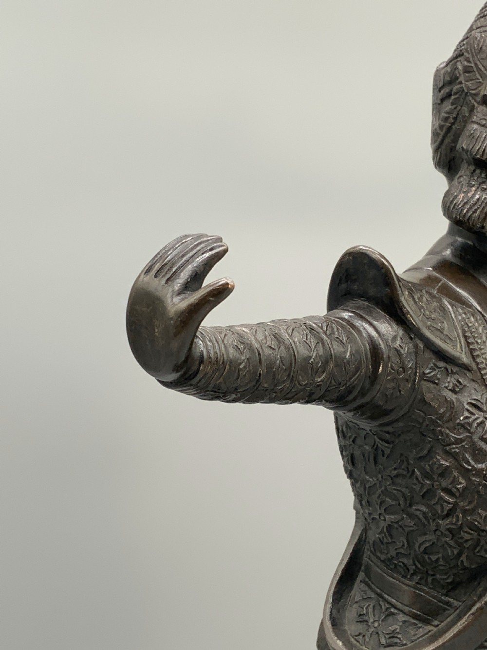 A dark bronze sculpture depicting a classical court dancer in ceremonial attire with a tall spired headdress, balanced on one foot atop an octagonal stepped base. View XIV