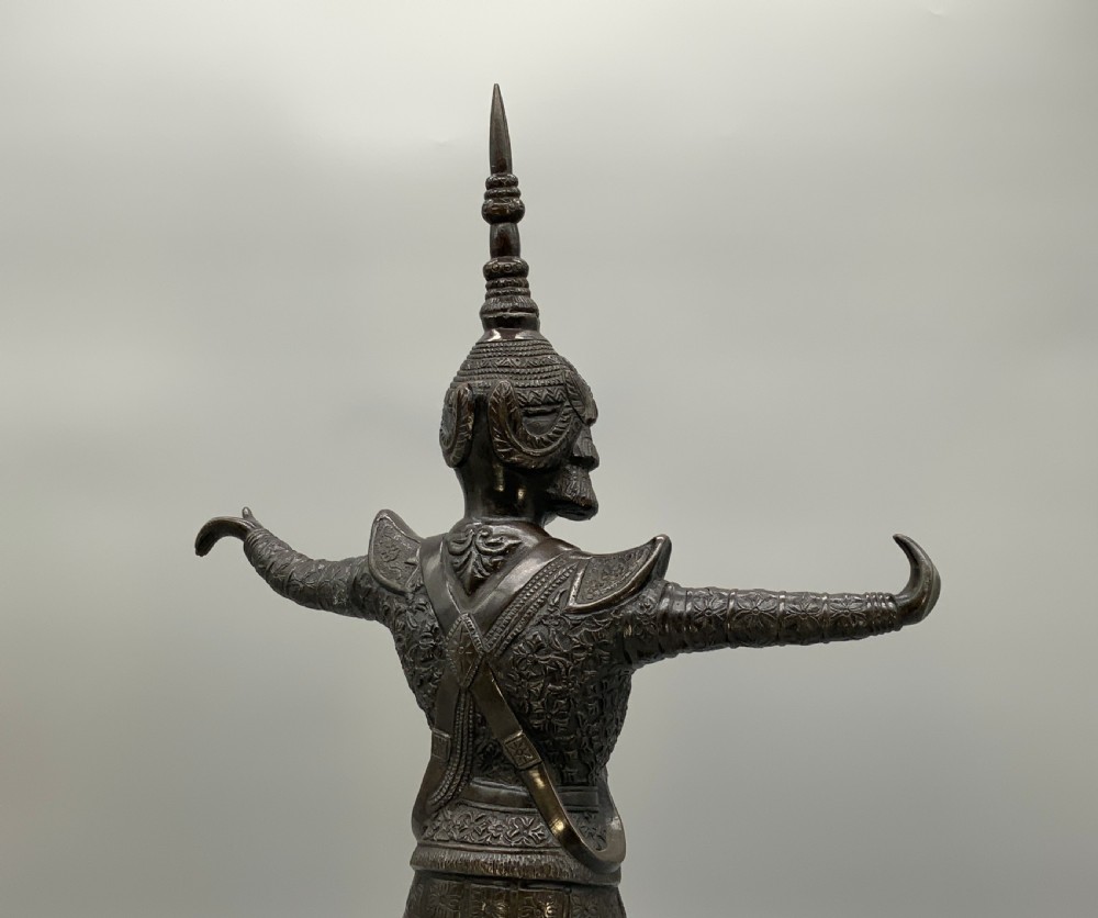 A dark bronze sculpture depicting a classical court dancer in ceremonial attire with a tall spired headdress, balanced on one foot atop an octagonal stepped base. View XVI