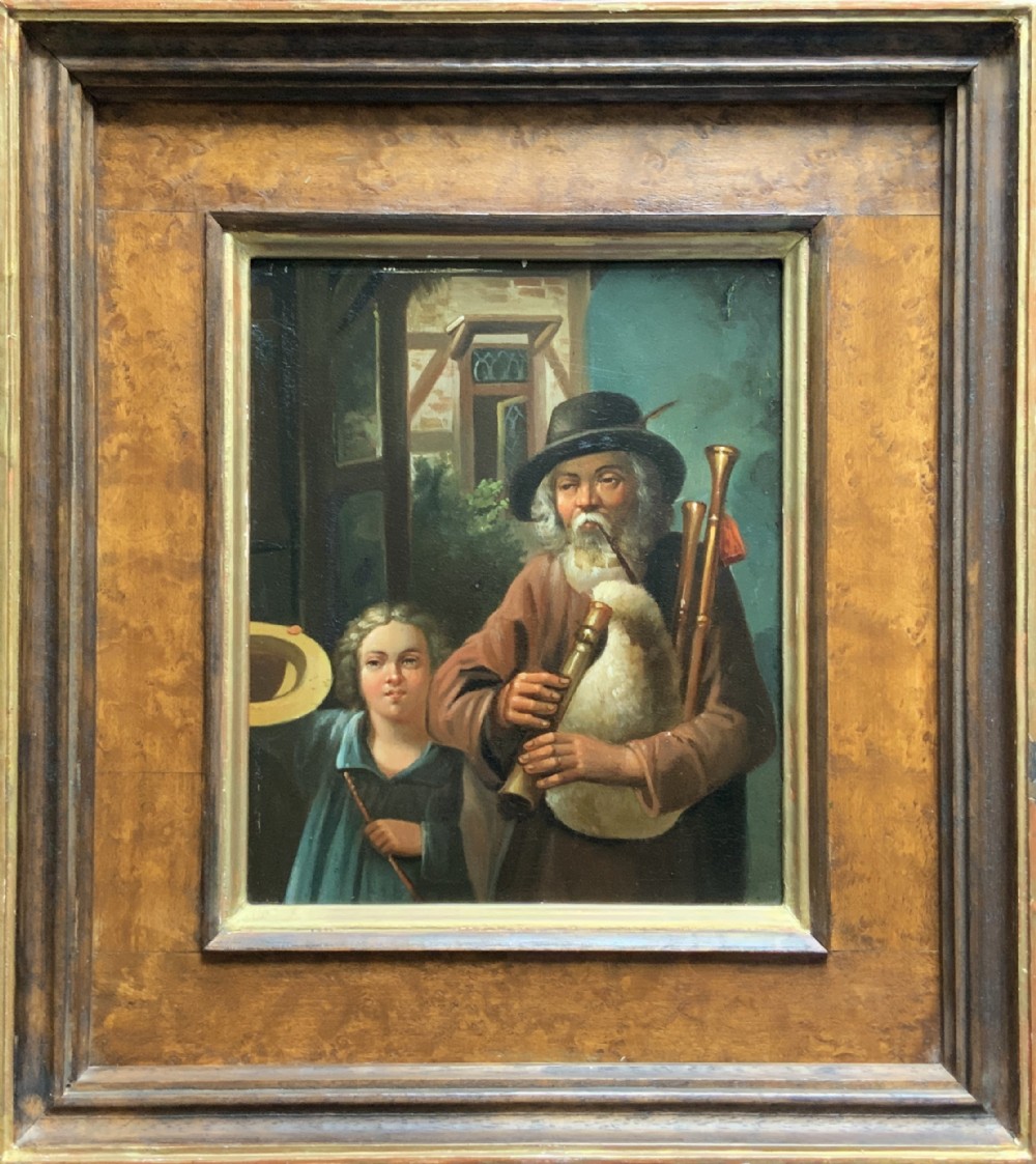 An antique oil painting in a deep burr wood frame depicting an older bearded musician playing a bagpipe alongside a child holding an extended hat.