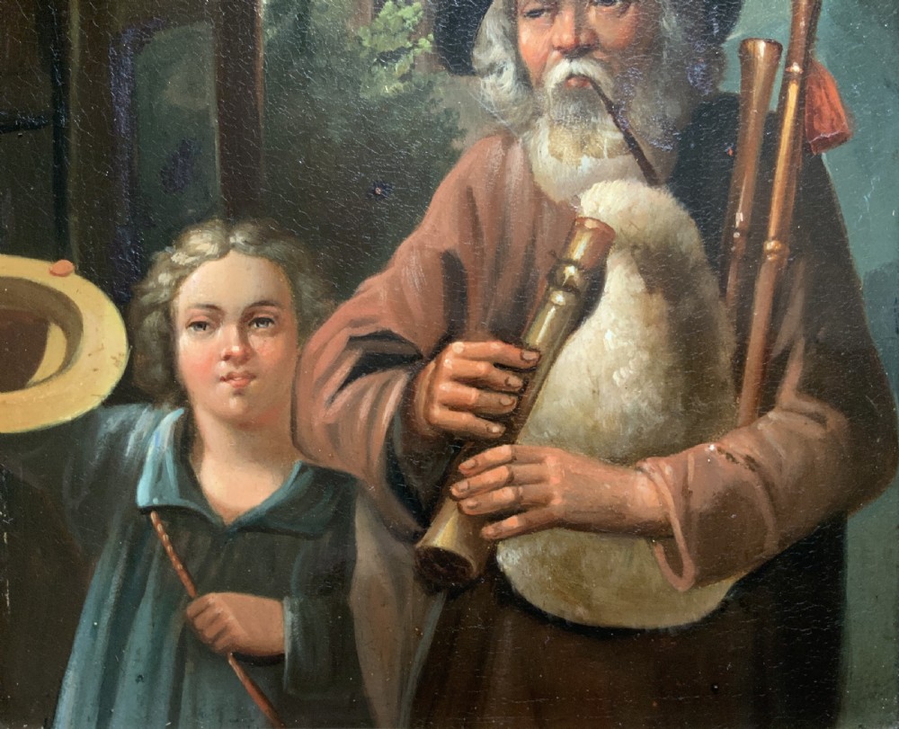 An antique oil painting in a deep burr wood frame depicting an older bearded musician playing a bagpipe alongside a child holding an extended hat. View IV
