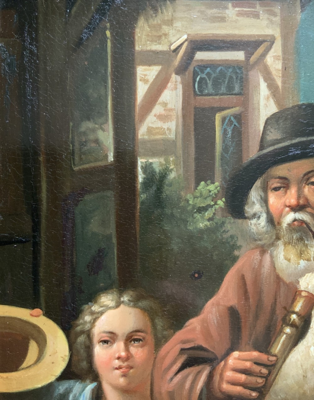 An antique oil painting in a deep burr wood frame depicting an older bearded musician playing a bagpipe alongside a child holding an extended hat. View VIII