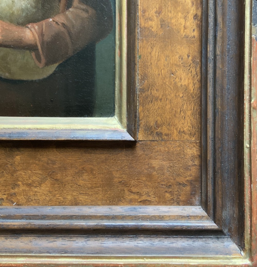 An antique oil painting in a deep burr wood frame depicting an older bearded musician playing a bagpipe alongside a child holding an extended hat. View IX