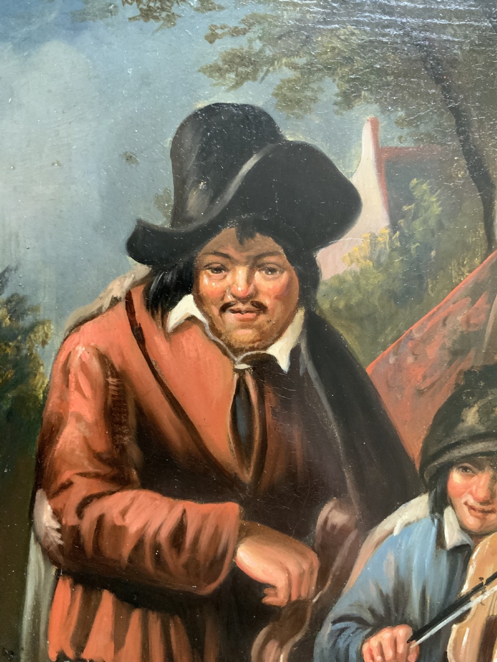 An antique oil painting depicting two musicians, a man and a boy playing a violin, set in a wide wooden frame with a gilded inner moulding. View IV
