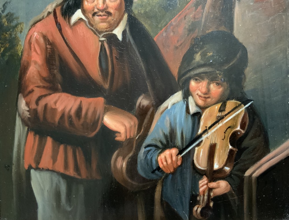 An antique oil painting depicting two musicians, a man and a boy playing a violin, set in a wide wooden frame with a gilded inner moulding. View VI