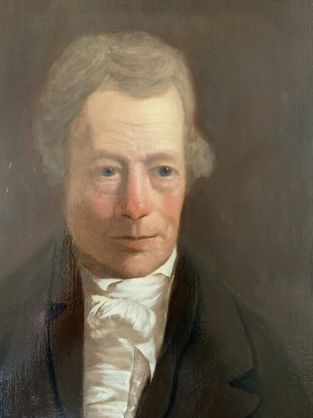 An early nineteenth-century portrait painting of a gentleman wearing a white cravat and dark coat, set within a carved gilt frame. View VI