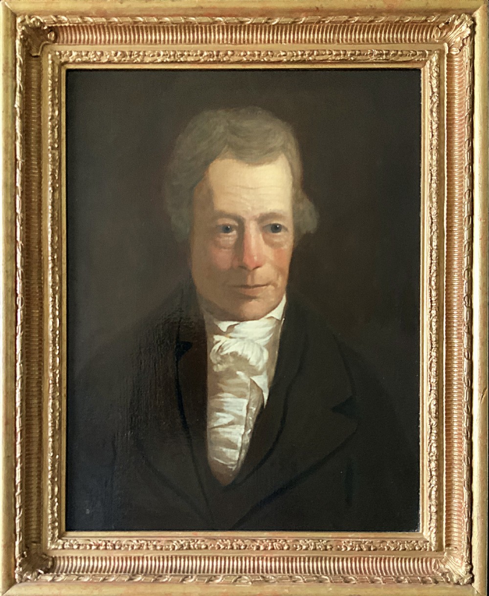 An early nineteenth-century portrait painting of a gentleman wearing a white cravat and dark coat, set within a carved gilt frame. View XI