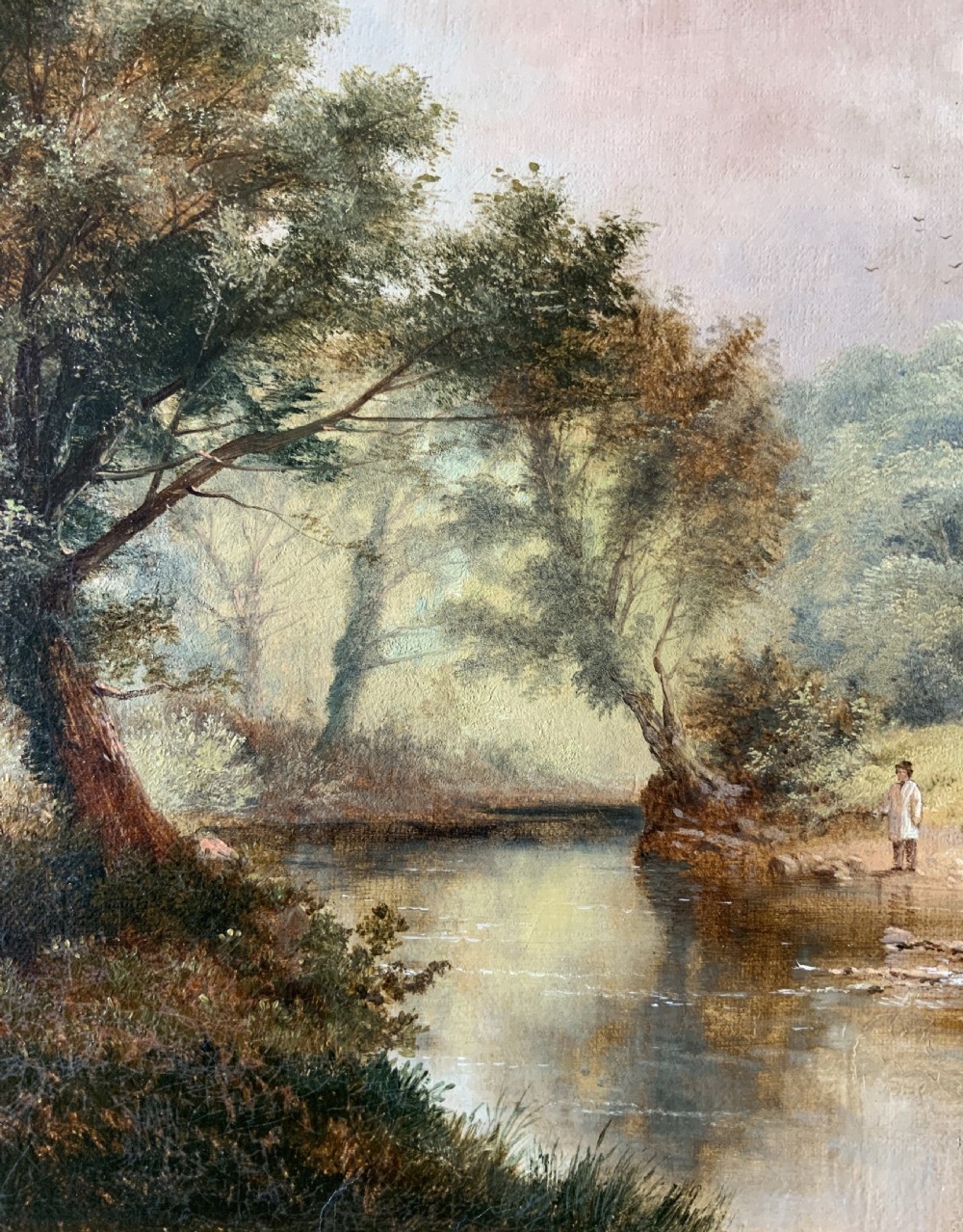 A 19th-century landscape oil painting depicting a river scene with trees and figures along the bank, housed in a green and gold moulded frame. View VII