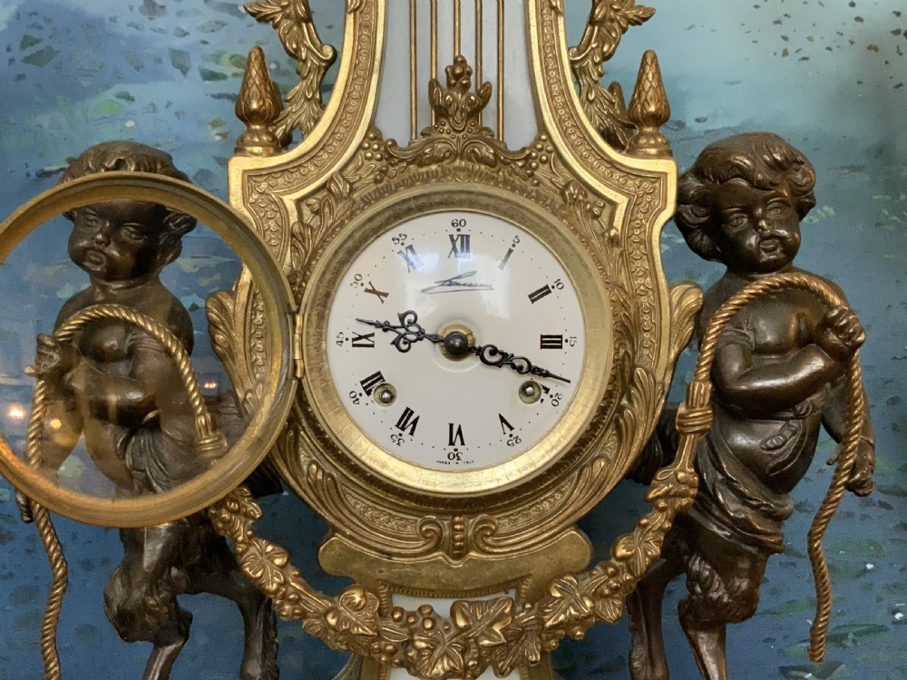 A three-piece antique clock garniture set featuring a central gilt bronze and white marble clock flanked by two matching multi-arm candelabra. View IX