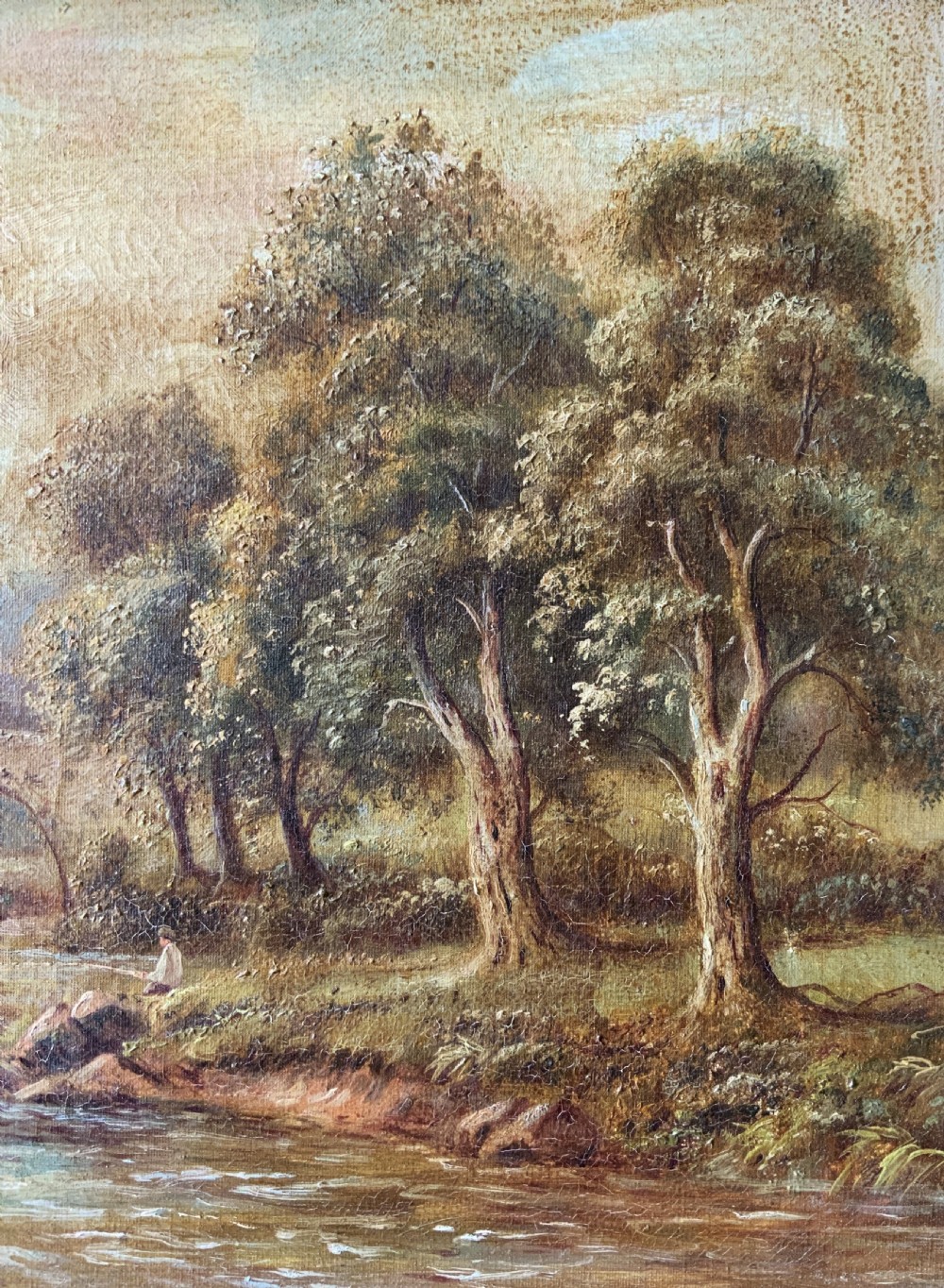 An antique oil painting depicting a tranquil river flowing through a wooded landscape with a stone bridge and cottage in the background, framed in polished dark wood. View IV