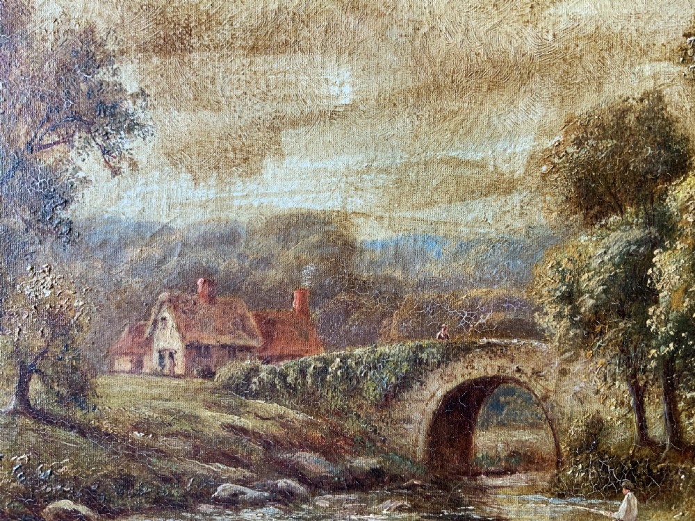 An antique oil painting depicting a tranquil river flowing through a wooded landscape with a stone bridge and cottage in the background, framed in polished dark wood. View IX
