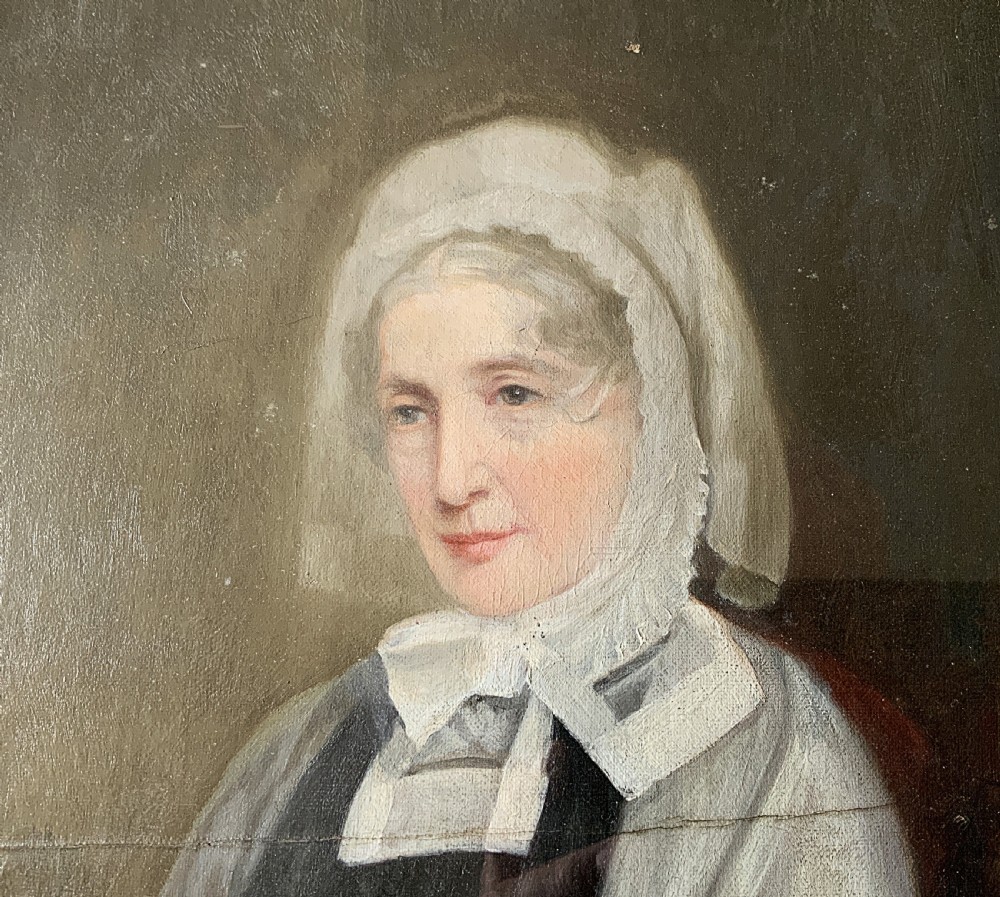A nineteenth-century oil portrait painting depicting a seated lady wearing a white lace bonnet and grey shawl, housed in a black ebonised frame with a pale inner slip. View V