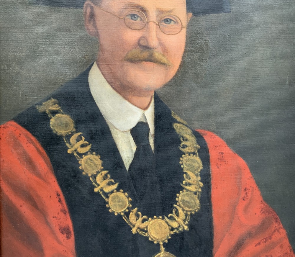 An oil portrait of a bespectacled man with a moustache wearing a tricorne hat, dark tie, red ceremonial robes, and a gold mayors chain of office, presented in a gilded wood frame. View VI