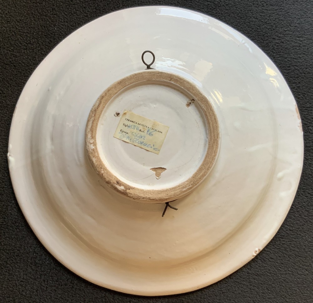 An 18th-century circular Spanish faience charger plate featuring a hand-painted equestrian figure framed by a blue patterned border and a yellow rim. View IX