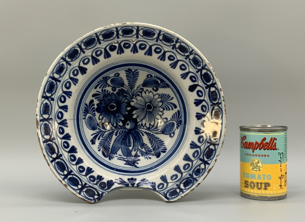 An 18th-century blue and white Dutch Delftware barbers bowl featuring hand-painted floral motifs and a semi-circular rim notch. View III
