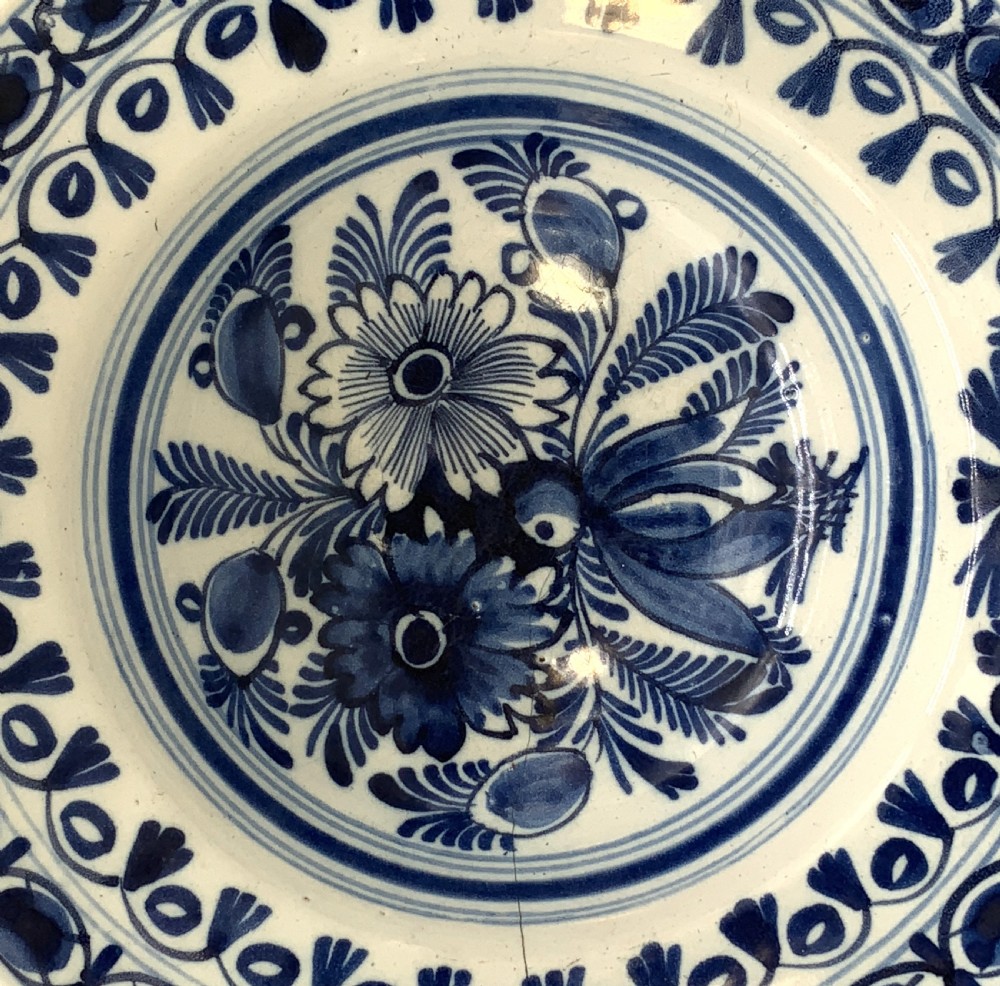 An 18th-century blue and white Dutch Delftware barbers bowl featuring hand-painted floral motifs and a semi-circular rim notch. View IV