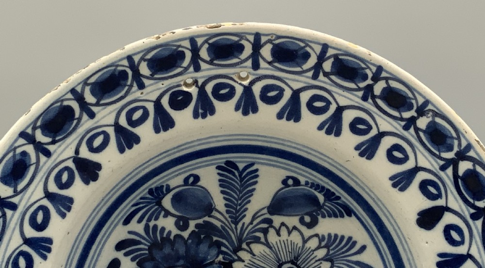 An 18th-century blue and white Dutch Delftware barbers bowl featuring hand-painted floral motifs and a semi-circular rim notch. View V