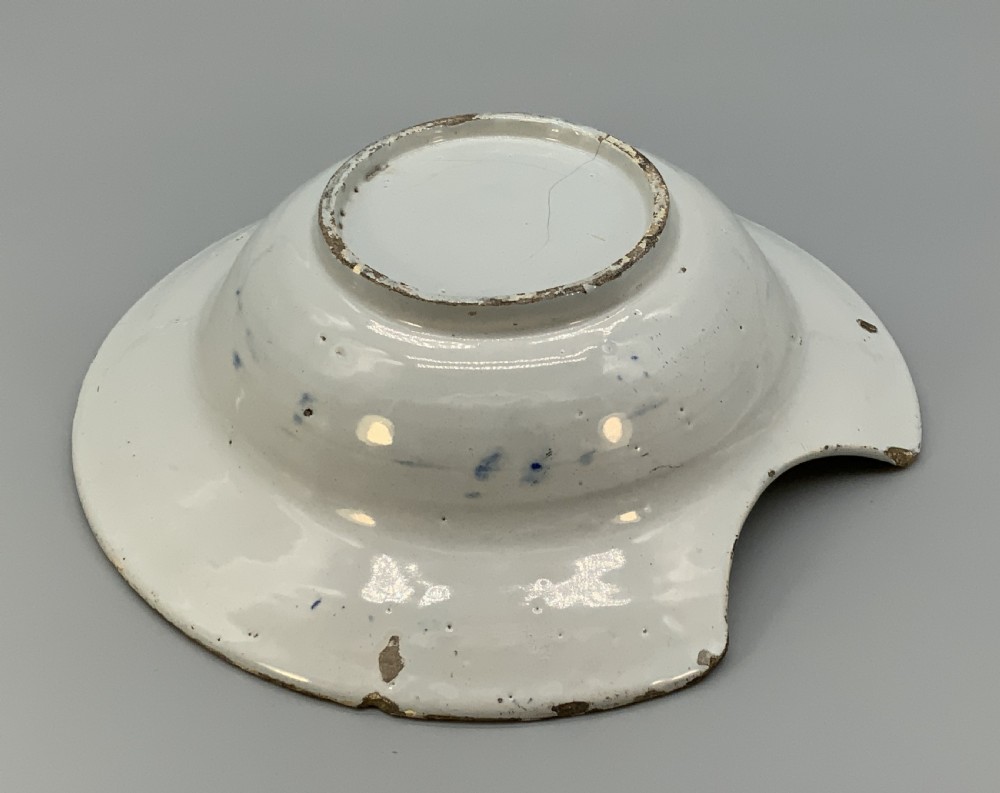 An 18th-century blue and white Dutch Delftware barbers bowl featuring hand-painted floral motifs and a semi-circular rim notch. View XIV