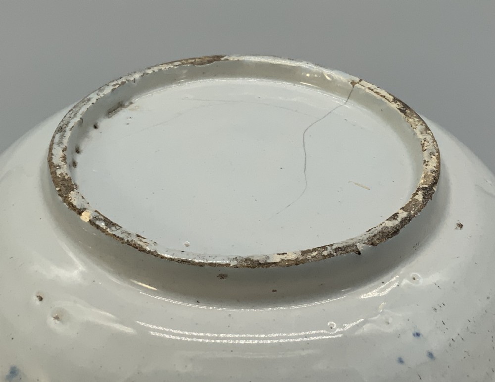 An 18th-century blue and white Dutch Delftware barbers bowl featuring hand-painted floral motifs and a semi-circular rim notch. View XV