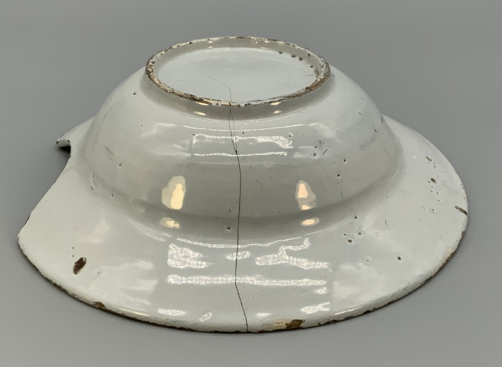 An 18th-century blue and white Dutch Delftware barbers bowl featuring hand-painted floral motifs and a semi-circular rim notch. View XVI