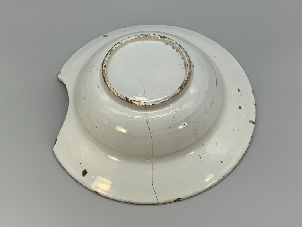 An 18th-century blue and white Dutch Delftware barbers bowl featuring hand-painted floral motifs and a semi-circular rim notch. View XVII