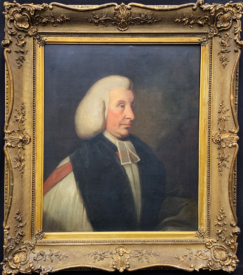 An 18th-century oil portrait of a clergyman in a powdered wig and clerical bands, framed in a carved giltwood frame.