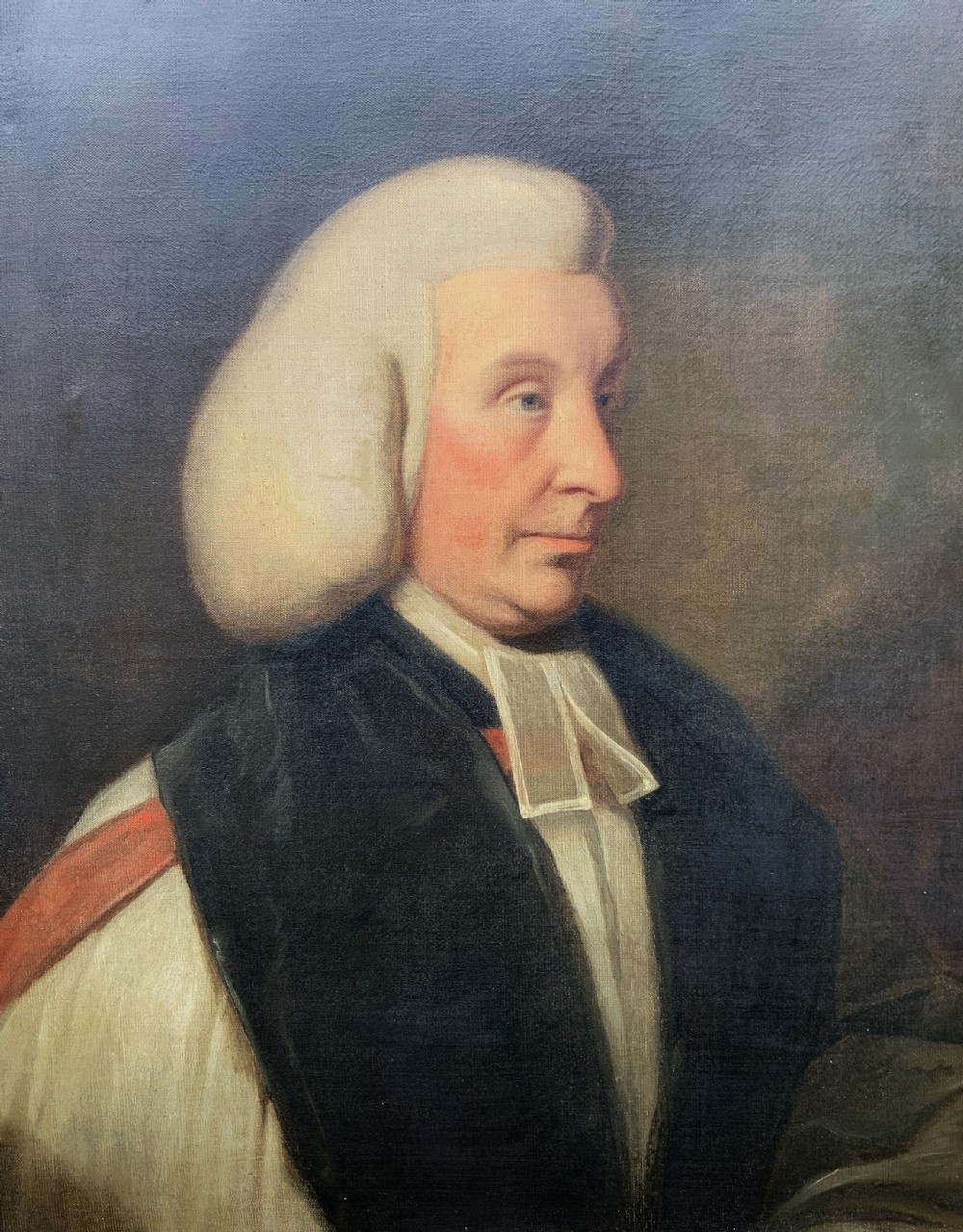 An 18th-century oil portrait of a clergyman in a powdered wig and clerical bands, framed in a carved giltwood frame. View VII