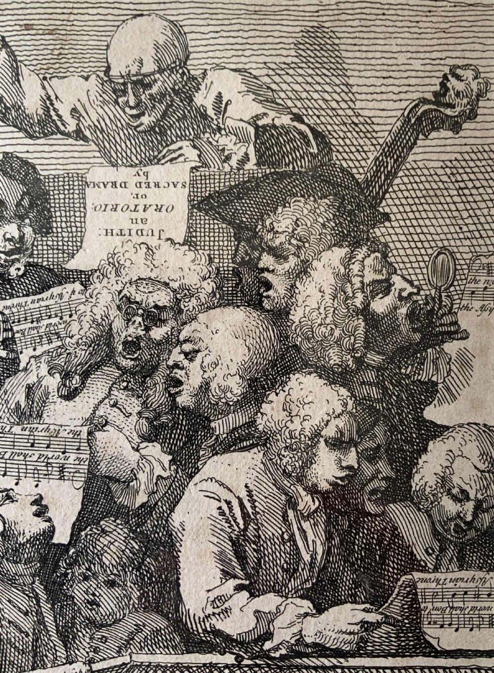 A framed monochrome etching depicting a group of 18th-century choir singers holding music scores, set within a cream mount and a black and gold moulding frame. View V