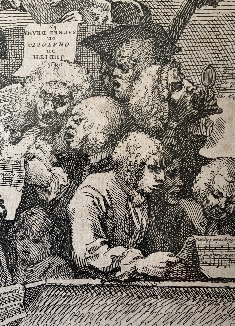 A framed monochrome etching depicting a group of 18th-century choir singers holding music scores, set within a cream mount and a black and gold moulding frame. View VI