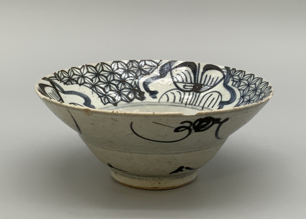 A 17th-century Chinese Swatow porcelain bowl featuring hand-painted underglaze blue geometric and floral motifs on an off-white glazed surface. View V