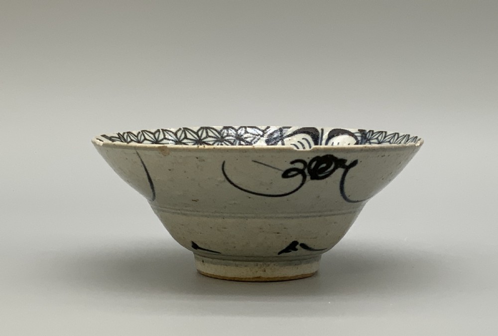 A 17th-century Chinese Swatow porcelain bowl featuring hand-painted underglaze blue geometric and floral motifs on an off-white glazed surface. View VI